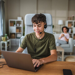 young teenage boy wear headset and play video games on laptop at home