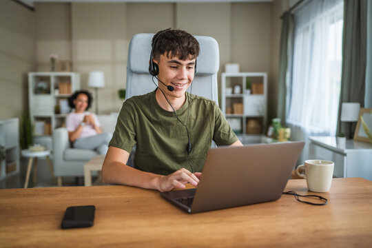 young teenage boy wear headset and play video games on laptop at home - Powered by Adobe