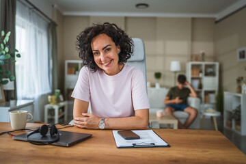 Portrait of beautiful mature curly hair woman sit in home office