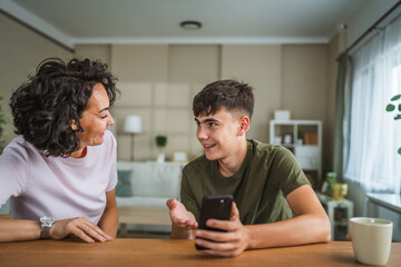 teenage boy share good news from mobile phone with his happy mother