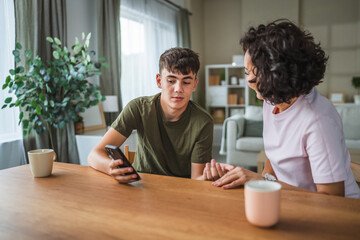 teenage boy share good news from mobile phone with his happy mother