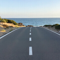 Scenic road leading to the sea with clear blue sky and coastline background