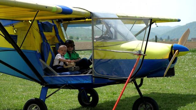 Brothers on board the plane, baby holding a toy, bigger child with pilot cap