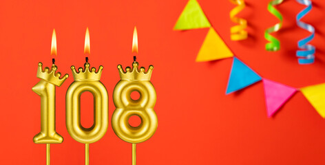 Number 108 birthday candle on an orange background with pennants