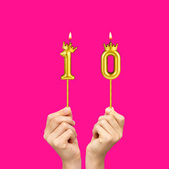 Birthday on a fuchsia background with the number 10 - Hands holding number-shaped candles