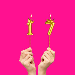 Hands holding number-shaped candles - Birthday number 17