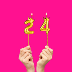 Birthday on a fuchsia background with the number 24 - Hands holding number-shaped candles