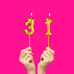 Hands holding number-shaped candles - Birthday number 31
