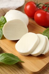Tasty mozzarella, tomatoes and basil on wooden table, closeup