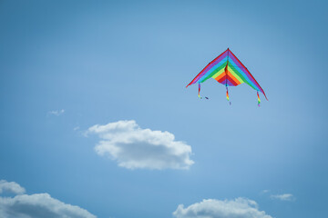 Colorful kite flying in blue sky, low angle view. Space for text