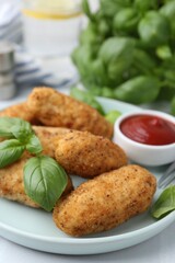 Tasty fried croquettes, basil and sauce on white tiled table, closeup