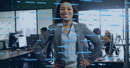 Standing businesswoman projecting confidence in open-plan office, with monitors and data overlay