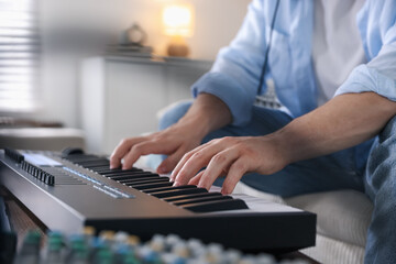 Man working with MIDI keyboard indoors, closeup