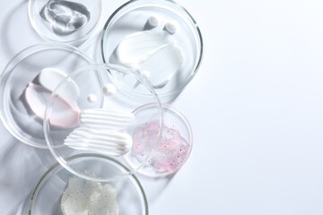 Different cosmetic products in Petri dishes on white background, flat lay. Space for text