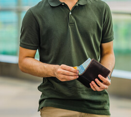 A man takes a rupiah note from a leather wallet, perfect for the design of a leather products catalogue.