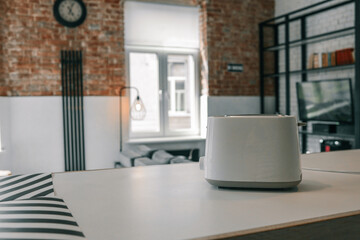 Minimalist white toaster on a modern kitchen counter in a cozy loft-style interior with exposed...