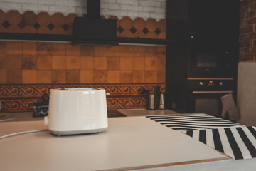 White toaster on a kitchen counter with vintage orange tile backsplash, black appliances, and a cozy eclectic interior design