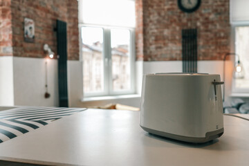 Minimalist white toaster on a modern kitchen counter in a cozy loft-style interior with exposed...