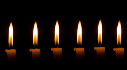 Seis velas encendidas alineadas sobre fondo negro en ambiente oscuro
