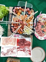 Culinary Delight: An enticing array of food items, including meat, vegetables, and skewers, is presented on a table, ready to be enjoyed, perfect for culinary and food-related projects.