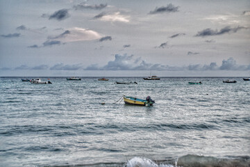 Fishing boat moored just off this Barbados beach, dramatic skies 