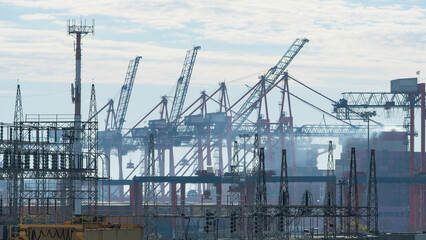 Power plant infrastructure against the backdrop of a busy container port with large cranes
