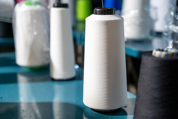 Close-up of a large white thread spool on a blue industrial table in a textile factory. the scene...