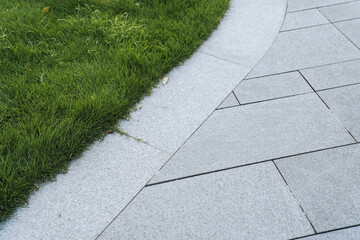 Fototapeta premium roadside of an concrete road with a stone curb in the background lawn with green grass