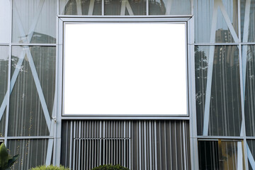 A mockup of a blank white billboard framed by a modern building facade, ideal for advertising