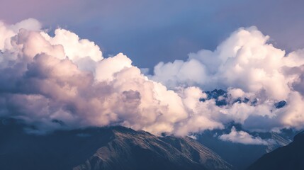 Majestic mountains partially covered by fluffy, dense clouds under a serene blue sky during daylight.
