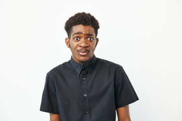 Black man looking confused, wearing a casual black shirt, standing against a plain white...