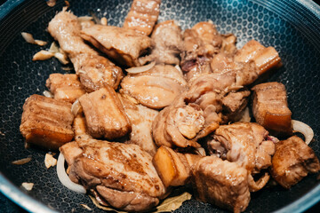 Savory chicken pork adobo simmering in a pan with rich sauce and spices.  with tender pieces marinating in a flavorful sauce. Aromatic spices fill the kitchen.