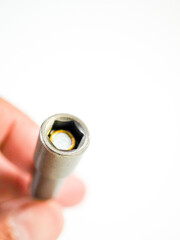 Holding a socket wrench head tool with metallic finish, isolated against a bright white background...