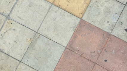 Multi-colored floor tiles with stains and scratches. The courtyard floor is paved with grey,...