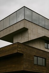 Slanted Office Block with Broken Floor Layers Using Aged Wood, Exposed Concrete, and Weathered Mirror Panels