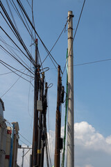 Tangled network of overhead power lines and cables against a clear blue sky.