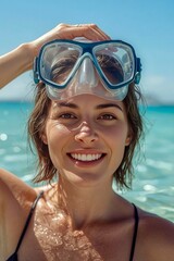 Portrait of a smiling woman wearing snorkel mask raised on her head against a serene turquoise ocean