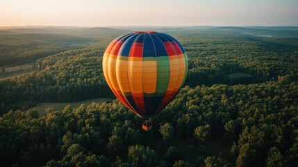 Colorful hot air balloon floats above lush forest canopy at sunrise