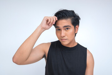Close-up portrait of a young Filipino man in a black muscle tee brushing hair back with a confident...
