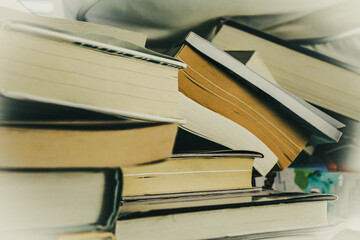 Fototapeta premium a stack of books randomly piled and tipping over. reading, learning, or knowledge abstract design element or background.