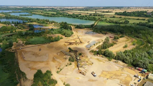 Aerial drone perspective of a quarry mining area with heavy machinery and aggregates minerals extraction in rural landscape near Little Paxton England UK