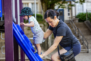 Mother Assisting Toddler on Slide in Vancouver Playground, BC, Canada