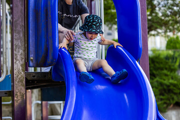 Toddler Playing on a Blue Slide with Parental Care in Vancouver Playground