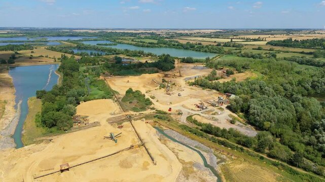 Aerial drone perspective of a quarry mining area with heavy machinery and aggregates minerals extraction in rural landscape near Little Paxton England UK