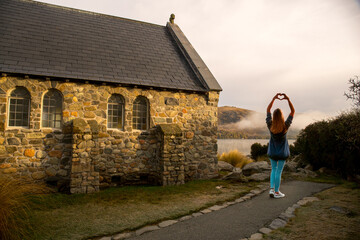 Woman making the heart symbol on the grounds of the Tekapo Chapel