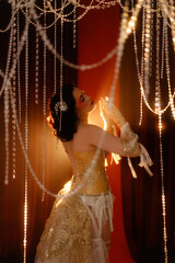 Brunette young woman, Caucasian, dressed as vintage cabaret dancer, posing front view under hanging...