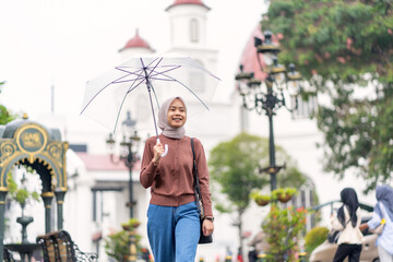 Indonesian Muslim Woman Walking with Umbrella in Kota Lama Semarang Old Town Indonesia