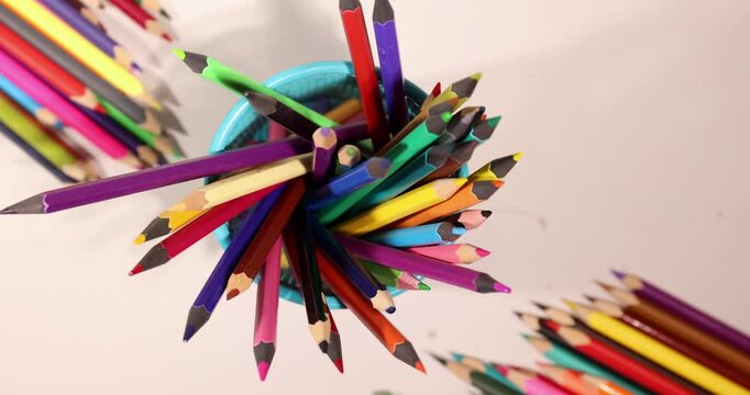 Preparing for back to school by gathering essential drawing tools. A hand holds vibrant pencils while colorful supplies surround a fun workspace. Ideal for art enthusiasts and students alike.