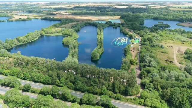 Aerial drone shot beautiful blue lakes and lush greenery with aqua water park play event near Little Paxton England UK