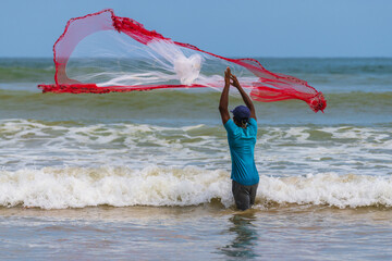 Sri Lankan fisherman cast a fishing net in the ocean, standing in the shallow waters.